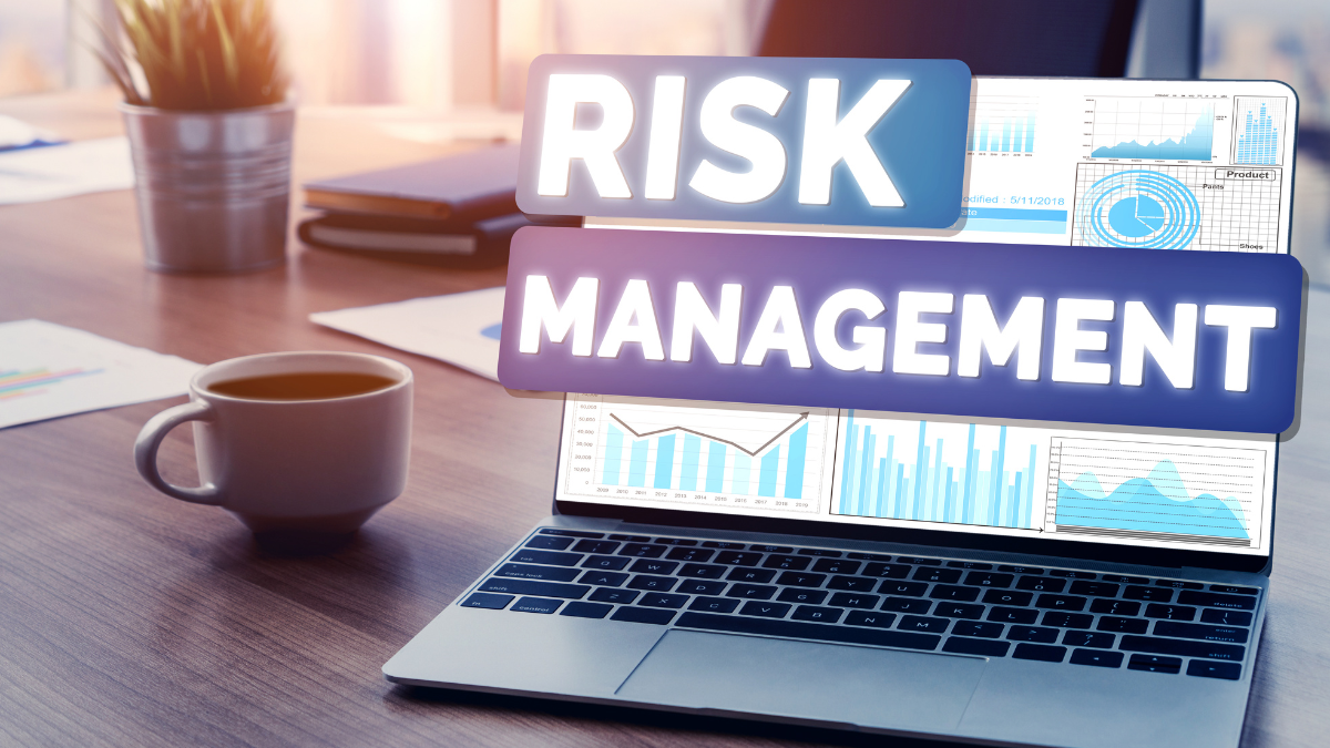 Risk Management concept displayed on a laptop screen with charts and graphs, accompanied by a coffee cup on a workplace desk.